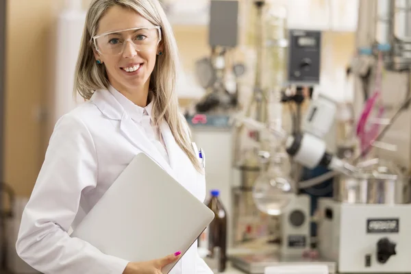 Jovem químico com computador portátil em pé no laboratório de química — Fotografia de Stock