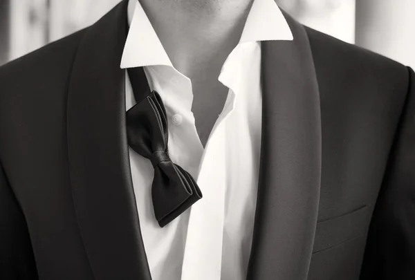 Close-up photo of man in tuxedo with open shirt and loose bow tie — Stok fotoğraf