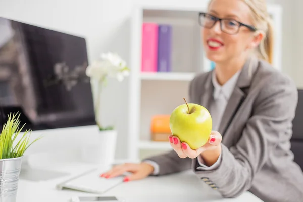 Femme d'affaires au bureau tenant pomme — Photo