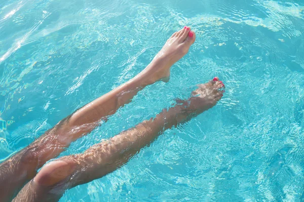 Pies desnudos sobre el agua de la piscina — Foto de Stock