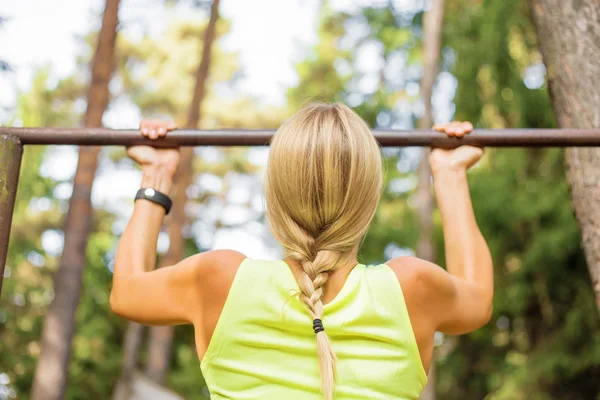 Atlético mulher fazendo pull ups — Fotografia de Stock