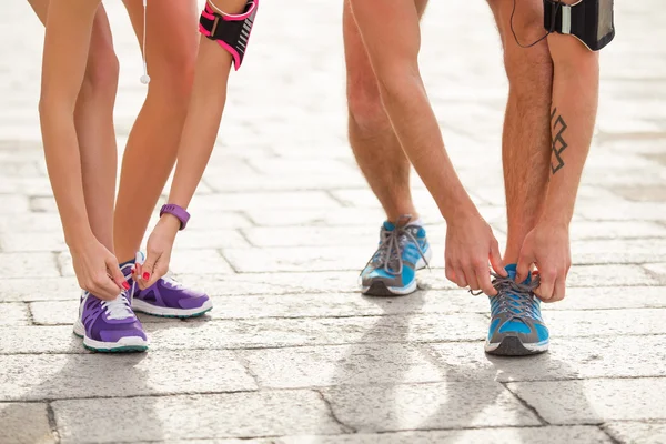 Pareja atando zapatos deportivos — Foto de Stock