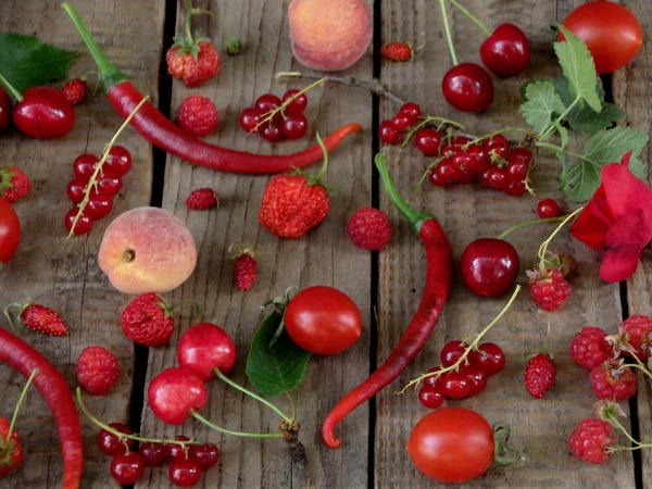 red fruits, vegetables and flowers on wooden background