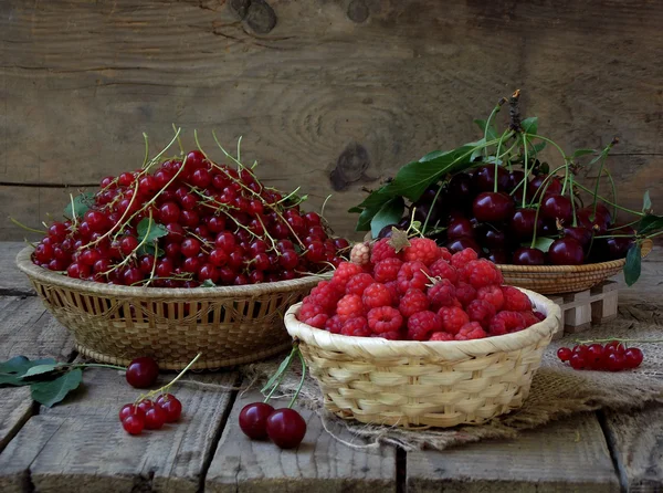 Frisches Obst und Beeren in Körben auf Holzgrund — Stockfoto