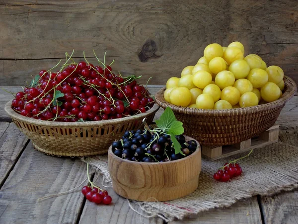 Frisches Obst und Beeren in Körben auf Holzgrund — Stockfoto