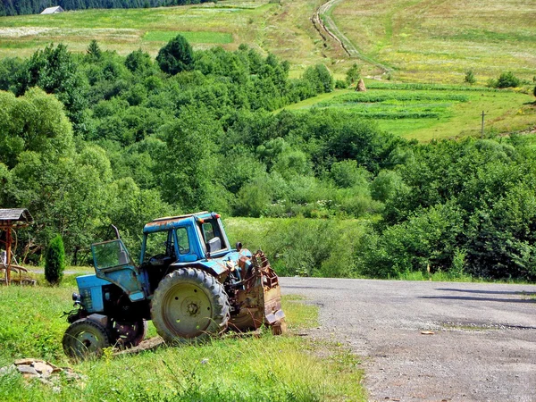 Yol kenarında üzerinde marka olmadan eski mavi traktör — Stok fotoğraf