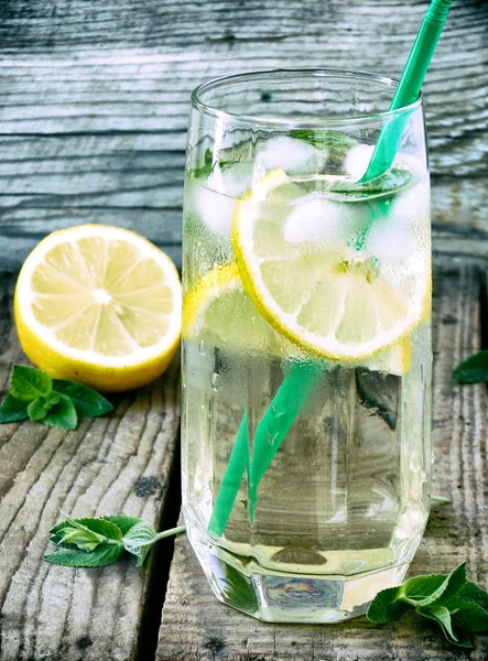 Ein großes Glas kalte Limonade mit Eis, Zitrone, Minzblättern und Stroh. — Stockfoto