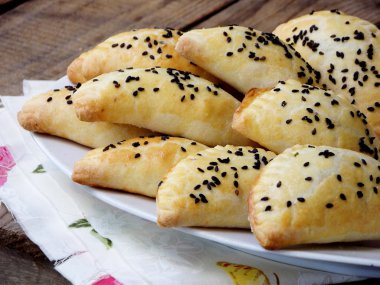 ahşap bir arka plan üzerinde bir tabak üzerinde siyah susam serpilir ev yapımı turta