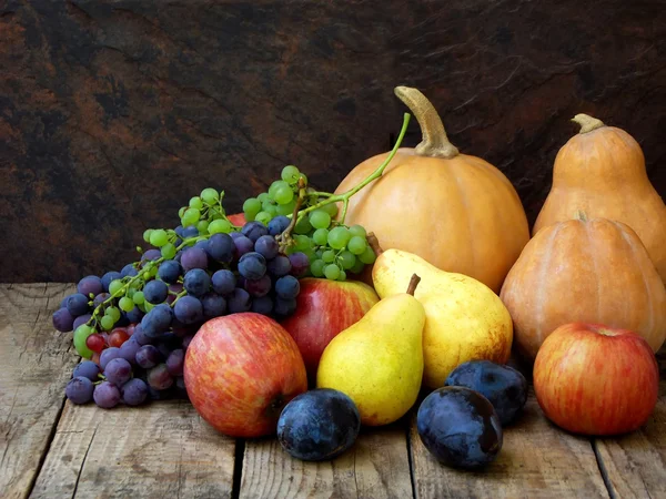 Натюрморт осенних фруктов: тыква, виноград, яблоко, груша, слива на деревянном фоне. селективный фокус — стоковое фото