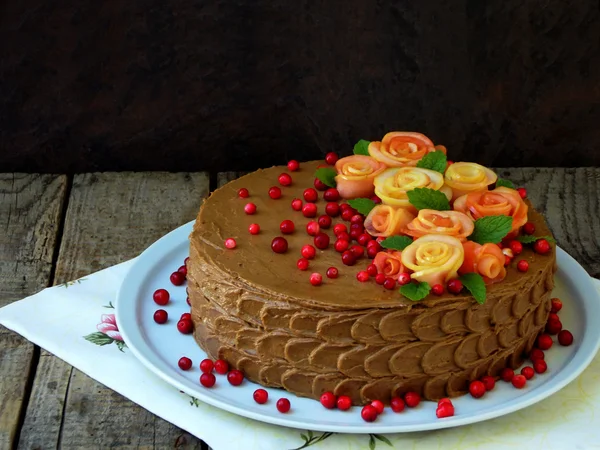 Gâteau au chocolat avec des roses faites de pommes et de canneberges sur un fond en bois — Photo