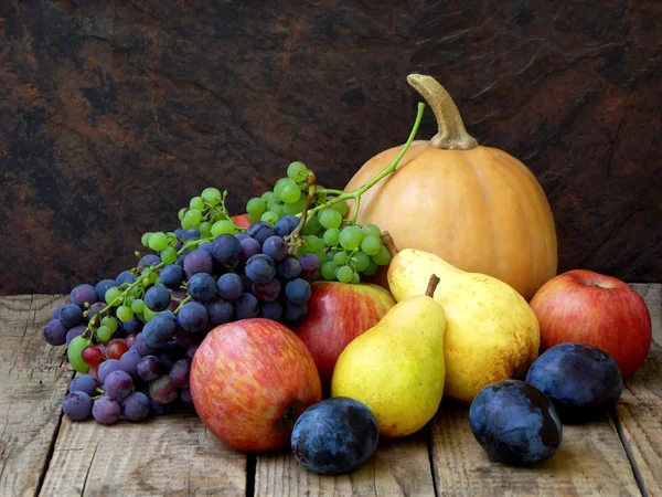 Натюрморт осенних фруктов: тыква, виноград, яблоко, груша, слива на деревянном фоне. селективный фокус — стоковое фото