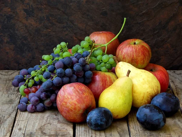 Натюрморт осенних фруктов: виноград, яблоки, груша, слива на деревянном фоне. селективный фокус — стоковое фото