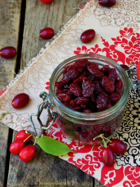 Gedroogde kornoelje (cornelian cherry berry) in pot op houten achtergrond. — Stockfoto