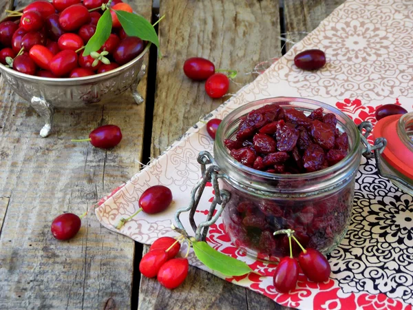 Gedroogde kornoelje (cornelian cherry berry) in pot op houten achtergrond. — Stockfoto