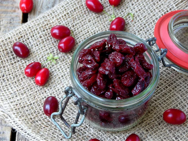 Gedroogde kornoelje (cornelian cherry berry) in pot op houten achtergrond. — Stockfoto