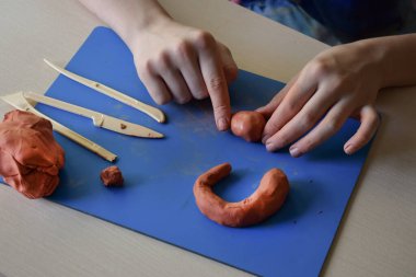 Doğal kilden düz heykel yapan çocuklar ilk adım olarak el yapımı el becerisi geliştirme konsepti için malzeme ve araçlar hazırlıyorlardı.