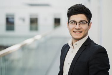 Gözlüklü iş adamı kameraya bakıyor, keyfi yerinde..