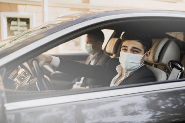 Kafkas görünümlü genç adamlar arabada oturuyorlar.