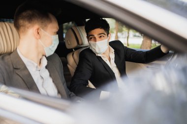 Arabada oturuyorlar. Covid 'in koruyucu maskelerini takıyorlar. 
