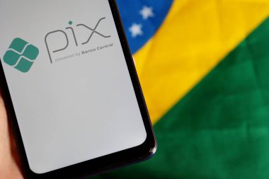 Bahia, Brezilya - 6 Ekim 2020. Arka planda Brezilya bayrağı olan ekranda Pix logosu olan akıllı telefon. Pix, Brezilya Merkez Bankası 'nın yeni acil ödeme sistemi..