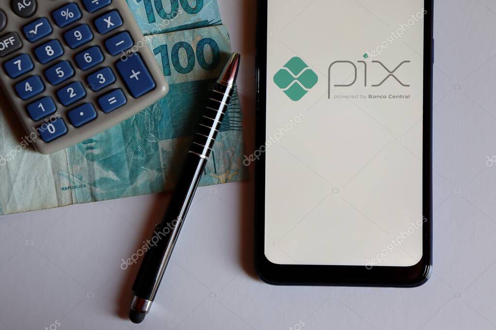 Brazil - October 9, 2020. PIX logo on smartphone screen on top of Brazilian Real banknotes. Pix is the new instant payment system from Central Bank of Brazil.