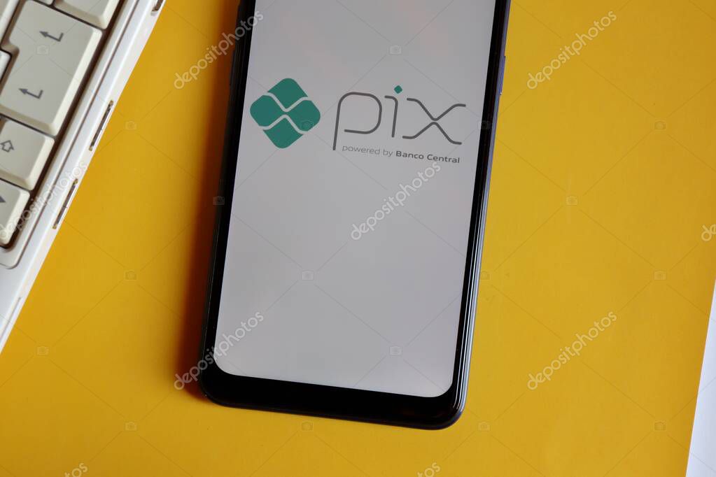Bahia, Brazil - October 9, 2020. Pix logo on smartphone screen and laptop on yellow background. Pix is the new instant payment system from Central Bank of Brazil (Banco Central do Brasil).