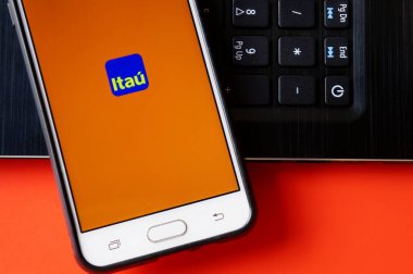 Bahia, Brezilya. 28 Nisan 2020. Banco Itau uygulaması arka planda dizüstü bilgisayarı olan akıllı telefon ekranında. Brezilya bankası. İnternet bankacılığı.