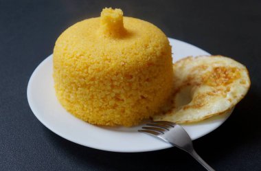 Brezilya kuskusu (cuscuz Brasileiro) ve sahanda yumurta. Kahvaltı konsepti. Geleneksel Brezilya yemeği mısır unundan hazırlandı.