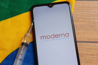 Bahia, Brezilya - 23 Mart 2021. Akıllı telefon ekranında Moderna Tıp Şirketi logosu ve Brezilya bayrağının tepesinde şırınga. Brezilya konseptinde Moderna Covid-19 aşısı.