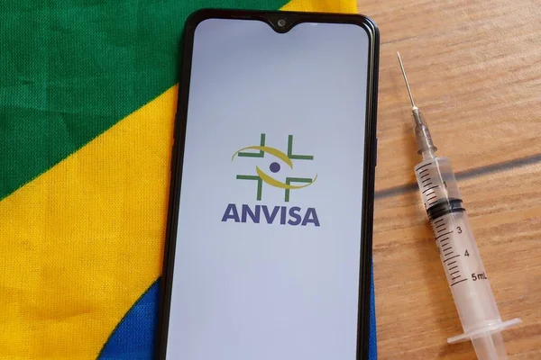 Bahia, Brezilya - 23 Mart 2021. Akıllı telefon ekranında anvize logosu ve Brezilya bayrağının tepesinde şırınga. Brezilya aşısı konsepti. Covid 19.