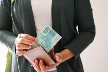 Brezilya parasıyla cüzdan tutan bir kadın. Ödeme, finans ve Brezilya ekonomisi kavramı.