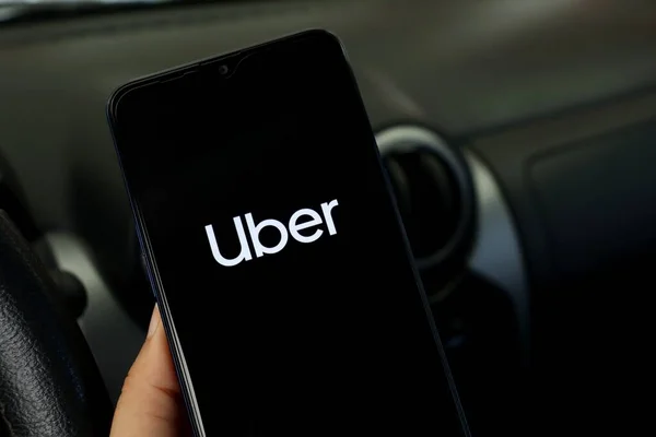 Bahia, Brezilya - 30 Nisan 2021: Uber uygulamalı akıllı telefonu olan bir arabada bulunan kişi. Kullanıcı logosu. 