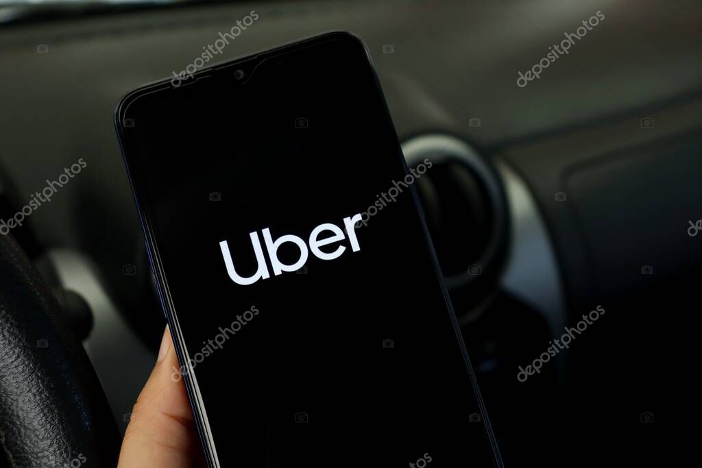 Bahia, Brazil - April 30, 2021: Person in a car holding smartphone with Uber app displayed. Uber logo.