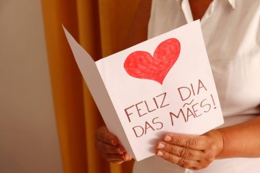 Annem Feliz Dia das Maes 'i (Anneler Günün kutlu olsun, Portekizce) hediye kartıyla tutuyor. Brezilya 'da Anneler Günü konsepti.