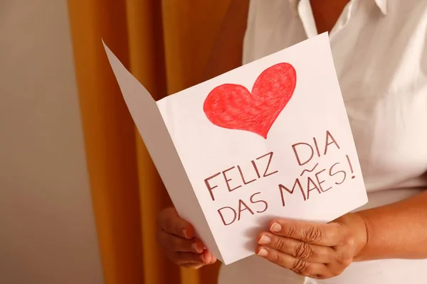 Annem Feliz Dia das Maes 'i (Anneler Günün kutlu olsun, Portekizce) hediye kartıyla tutuyor. Brezilya 'da Anneler Günü konsepti.