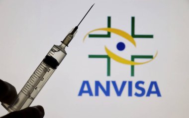 Bahia, Brezilya - 3 Mayıs 2021: Anvize logosu ekranda ve elinde şırıngayla sergileniyor. Covid-19 aşı konsepti. 