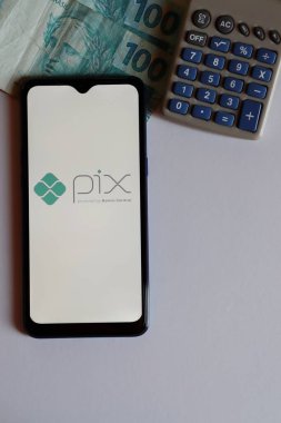 Bahia, Brazil - October 9, 2020: PIX logo on smartphone screen on office desk. Pix is the new instant payment system from Central Bank of Brazil.Vertical photo.