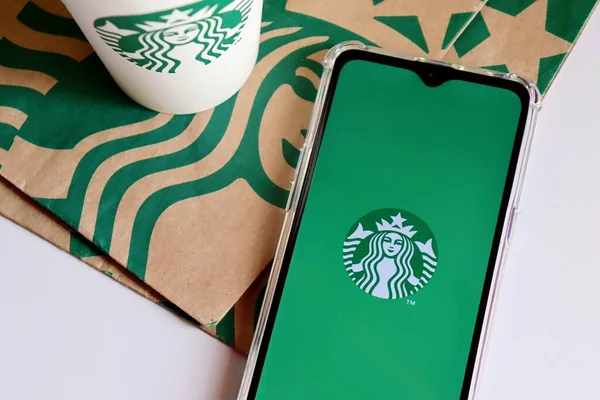 Bahia, Brezilya - 30 Eylül 2020: Starbucks uygulaması akıllı telefon ekranında kağıt torbaların üstünde. Starbucks uygulaması mağazada ödeme yapmak ya da sırayı atlamak için uygun bir yoldur..