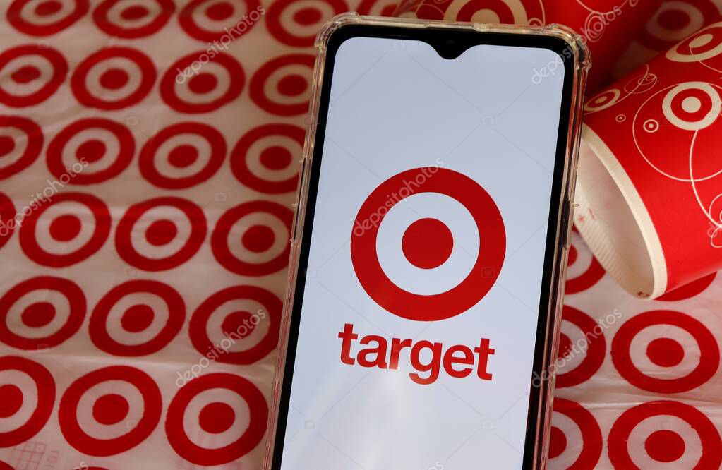 Bahia, Brazil - September 30, 2020. Target Store logo on smartphone screen with Target cups and shopping bag in the background. Hypermarket.