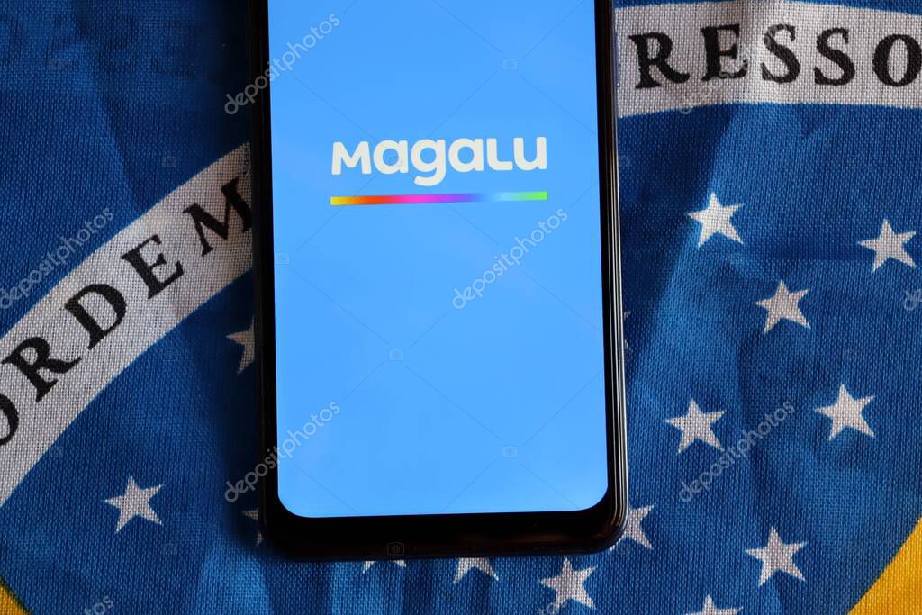 Bahia, Brazil - October 6, 2020: Magalu App on smartphone screen on top of Brazilian flag. Magazine Luiza, or Magalu, is a Brazilian retail company.