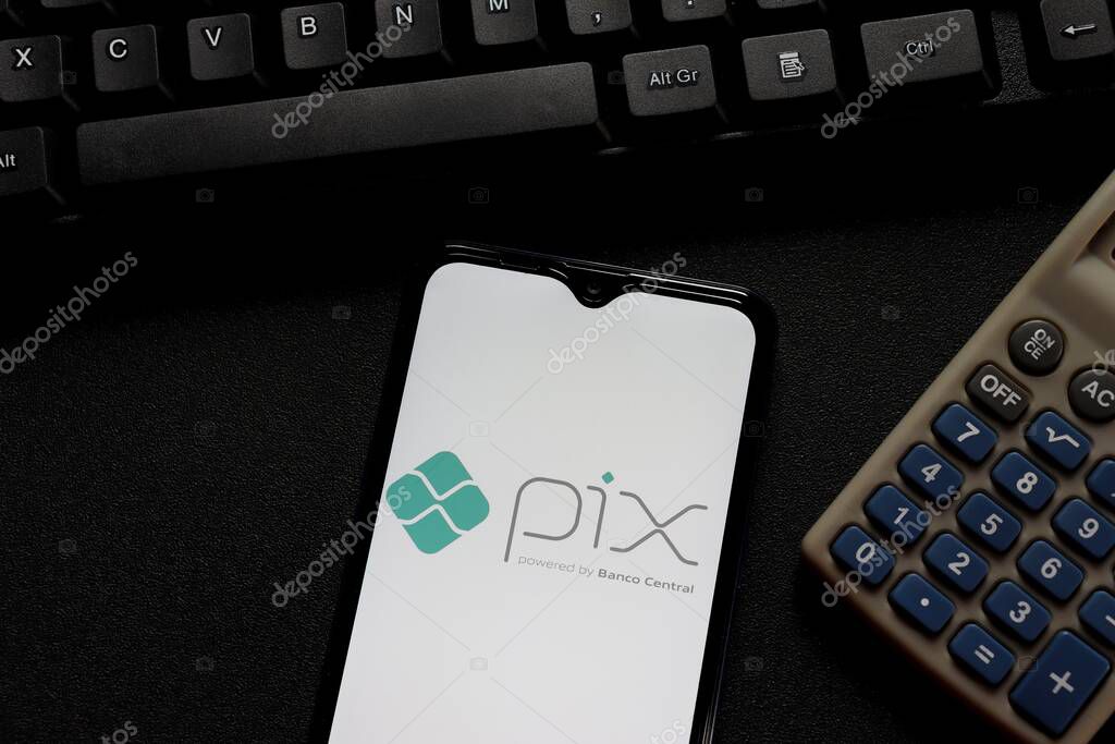 Bahia, Brazil - October 27, 2020. Pix logo on smartphone screen with calculator and computer keyboard. Pix is the new instant payment system from Central Bank of Brazil.