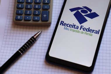 Bahia, Brezilya - 25 Şubat 2025: Receita Federal - Meu imposto de Renda (Brezilya Federal Gelir Dairesi) logosu ofis masasındaki akıllı telefon ekranında. Brezilya 'da gelir vergisi beyanı.