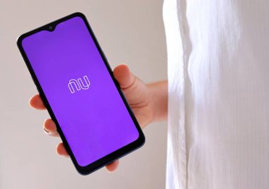Bahia, Brezilya - 6 Ocak 2021: Brezilya dijital bankası olan Nubank uygulamalı akıllı telefonu ekranda tutan kadın.