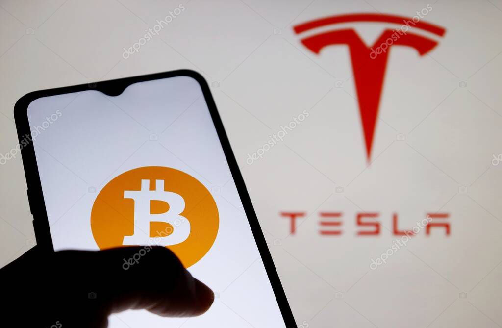 Bahia, Brazil - March 26, 2021: Bitcoin logo on smartphone screen with Tesla logo displayed in the background. Tesla cars can be bought in Bitcoin.