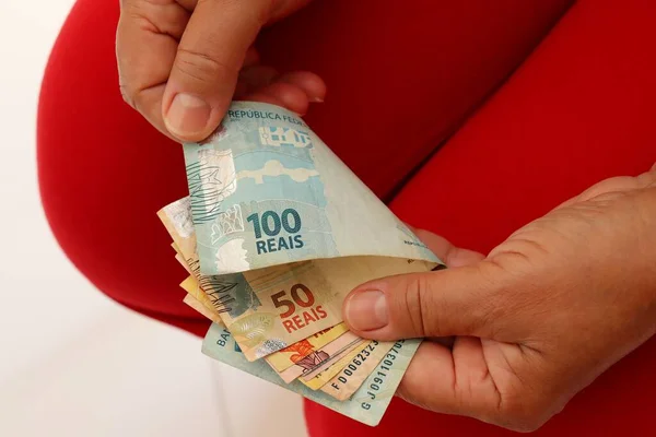 Woman counting Brazilian Real banknotes. Brazilian currency. Salary, finance, inflation concept.