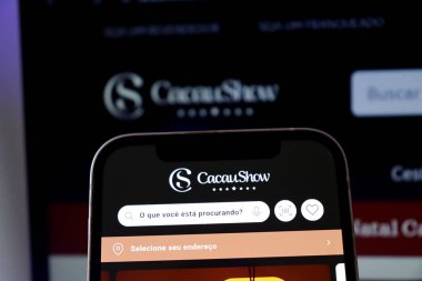 Salvador, Brezilya - 4 Aralık 2025: Cacau Show çikolata dükkanı logosu akıllı telefon ekranında. Brezilya Kakao Fuarı logosu.