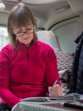 Bir bayan motor Homer eğlence aracında oturuyor ve bir günlük yazıyor. Gözlüklü bir gezgin. Dikey format..