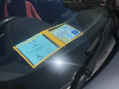 Bir arabanın ön camında engelli park izni gösterilir.