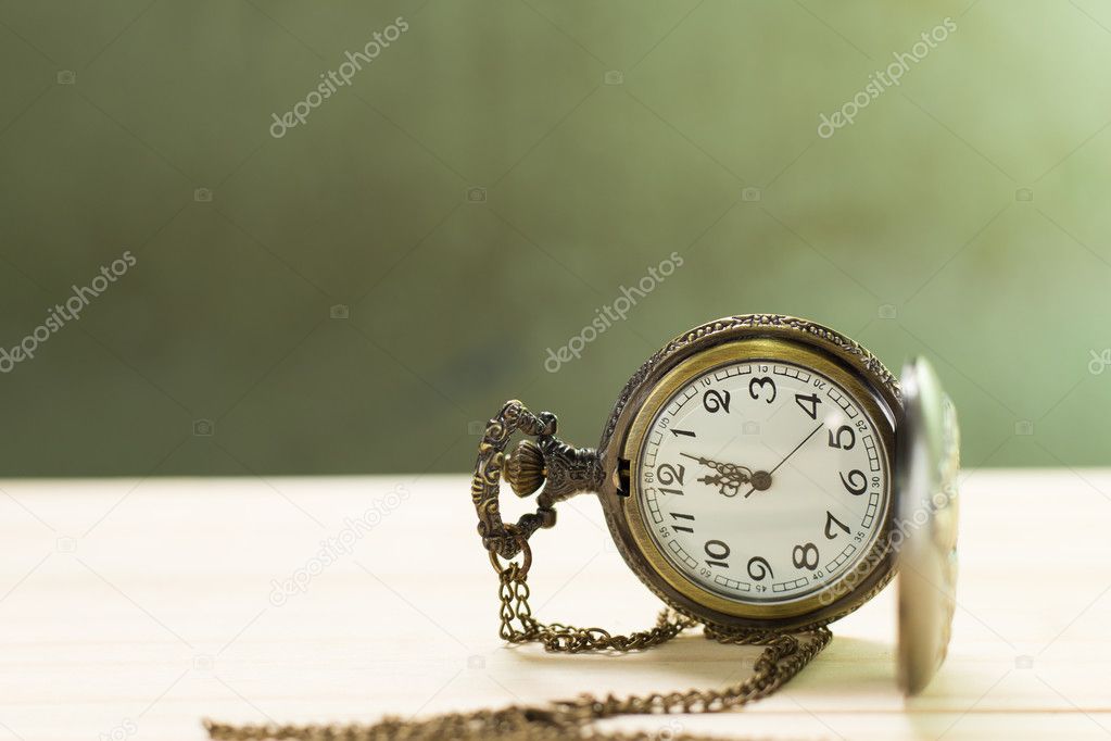 Antique clock on the wooden floor and green wall Background.
