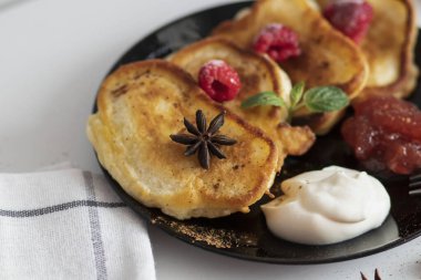 Krepli kahvaltı tabakta, ekşi krema ve asfalt. Krepler beyaz bir masanın üstünde ve adam elinde tutuyor..